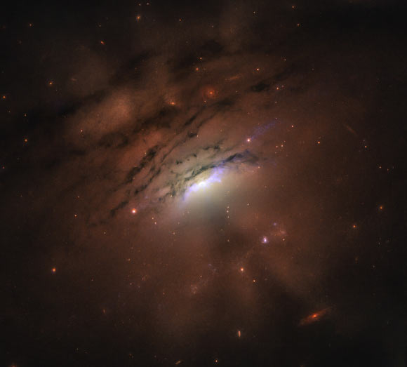 This Hubble image of the nearby active galaxy IC 5063 reveals a mixture of bright rays and dark shadows coming from the blazing core, home of a supermassive black hole. Image credit: Credits: NASA / ESA / Hubble / STScI / W.P. Maksym, CfA.