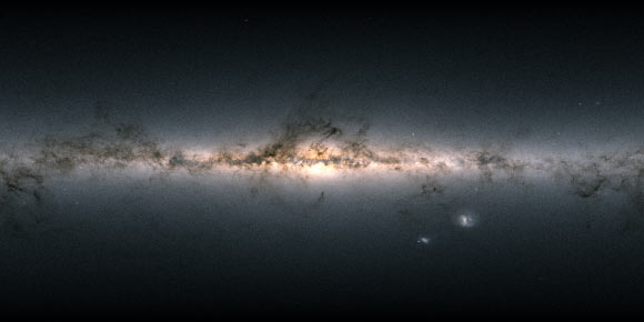 Data from more than 1.8 billion stars have been used to create this map of the entire sky. It shows the total brightness and color of stars observed by ESA’s Gaia satellite and released as part of Gaia’s Early Data Release 3. Brighter regions represent denser concentrations of bright stars, while darker regions correspond to patches of the sky where fewer and fainter stars are observed. The color of the image is obtained by combining the total amount of light with the amount of blue and red light recorded by Gaia in each patch of the sky. The bright horizontal structure that dominates the image is the plane of our Milky Way Galaxy. It is actually a flattened disk seen edge-on that contains most of the Galaxy’s stars. In the middle of the image, the Galactic center appears bright, and thronged with stars. Darker regions across the Galactic plane correspond to foreground clouds of interstellar gas and dust, which absorb the light of more distant stars. Many of these clouds conceal stellar nurseries where new generations of stars are currently being born. Dotted across the image are also many globular and open clusters, as well as entire galaxies beyond our own. The two bright objects in the lower right of the image are the Large and Small Magellanic Clouds, two dwarf galaxies orbiting the Milky Way. Image credit: ESA / Gaia / DPAC / CC BY-SA 3.0 IGO / A. Moitinho.