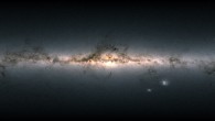 Data from more than 1.8 billion stars have been used to create this map of the entire sky. It shows the total brightness and color of stars observed by ESA’s Gaia satellite and released as part of Gaia’s Early Data Release 3. Brighter regions represent denser concentrations of bright stars, while darker regions correspond to patches of the sky where fewer and fainter stars are observed. The color of the image is obtained by combining the total amount of light with the amount of blue and red light recorded by Gaia in each patch of the sky. The bright horizontal structure that dominates the image is the plane of our Milky Way Galaxy. It is actually a flattened disk seen edge-on that contains most of the Galaxy’s stars. In the middle of the image, the Galactic center appears bright, and thronged with stars. Darker regions across the Galactic plane correspond to foreground clouds of interstellar gas and dust, which absorb the light of more distant stars. Many of these clouds conceal stellar nurseries where new generations of stars are currently being born. Dotted across the image are also many globular and open clusters, as well as entire galaxies beyond our own. The two bright objects in the lower right of the image are the Large and Small Magellanic Clouds, two dwarf galaxies orbiting the Milky Way. Image credit: ESA / Gaia / DPAC / CC BY-SA 3.0 IGO / A. Moitinho.