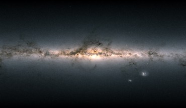 Data from more than 1.8 billion stars have been used to create this map of the entire sky. It shows the total brightness and color of stars observed by ESA’s Gaia satellite and released as part of Gaia’s Early Data Release 3. Brighter regions represent denser concentrations of bright stars, while darker regions correspond to patches of the sky where fewer and fainter stars are observed. The color of the image is obtained by combining the total amount of light with the amount of blue and red light recorded by Gaia in each patch of the sky. The bright horizontal structure that dominates the image is the plane of our Milky Way Galaxy. It is actually a flattened disk seen edge-on that contains most of the Galaxy’s stars. In the middle of the image, the Galactic center appears bright, and thronged with stars. Darker regions across the Galactic plane correspond to foreground clouds of interstellar gas and dust, which absorb the light of more distant stars. Many of these clouds conceal stellar nurseries where new generations of stars are currently being born. Dotted across the image are also many globular and open clusters, as well as entire galaxies beyond our own. The two bright objects in the lower right of the image are the Large and Small Magellanic Clouds, two dwarf galaxies orbiting the Milky Way. Image credit: ESA / Gaia / DPAC / CC BY-SA 3.0 IGO / A. Moitinho.
