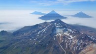 An aerial oblique photo of the volcanoes in the Islands of Four Mountains, Alaska, taken in July 2014. In the center is the summit of Mount Tana. Behind Tana are (left to right) Herbert, Cleveland, and Carlisle volcanoes. Image credit: John Lyons / USGS.