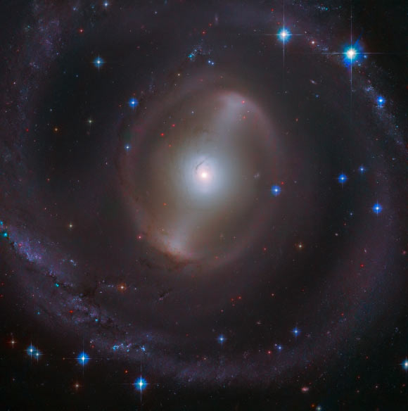 This Hubble image shows the central region of NGC 2217, a barred spiral galaxy some 83 million light-years away in the constellation Canis Major. This image is made up of observations from Hubble’s Advanced Camera for Surveys (ACS) in the optical part of the spectrum. It was colorized with data from the Panoramic Survey Telescope and Rapid Response System (Pan-STARRS). Image credit: NASA / ESA / Hubble / J. Dalcanton / Judy Schmidt, www.geckzilla.com.