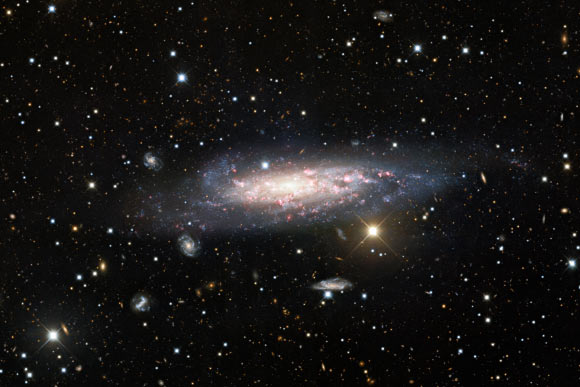 A long-exposure observation lasting 70 min from the Nicholas U. Mayall 4-m Telescope at Kitt Peak National Observatory, a Program of NSF’s NOIRLab, reveals NGC 1003 in glorious detail. This spiral galaxy resides in front of a galaxy cluster and the long exposure time of this deep observation allowed usually overlooked red background cluster galaxies to be captured. Image credit: KPNO / NOIRLab / NSF / AURA / Maria T. Patterson, New Mexico State University / Travis Rector, University of Alaska Anchorage / Mahdi Zamani & Davide de Martin.
