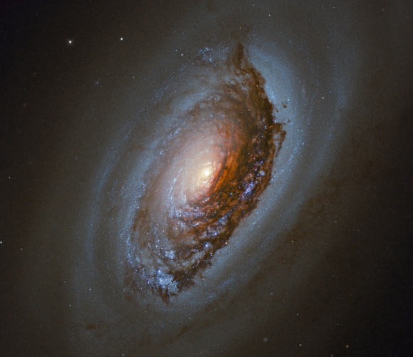This Hubble image shows Messier 64, a spiral galaxy located some 17 million light-years away in the constellation of Coma Berenices. This color composite was made from separate exposures taken in the visible, near-infrared and ultraviolet regions of the spectrum with Hubble’s Wide Field Camera 3 (WFC3). Five filters were used to sample various wavelengths. The color results from assigning different hues to each monochromatic image associated with an individual filter. Image credit: NASA / ESA / Hubble / J. Lee / PHANGS-HST Team / Judy Schmidt, www.geckzilla.com.