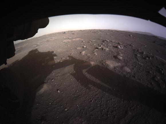 This is the first high-resolution, color image to be sent back by the Hazard Cameras (Hazcams) on the underside of NASA’s Perseverance Mars rover after its landing on February 18, 2021. Image credit: NASA / JPL-Caltech.