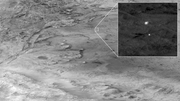 The descent stage holding NASA’s Perseverance rover can be seen falling through the Martian atmosphere, its parachute trailing behind, in this image taken on February 18, 2021, by the High Resolution Imaging Experiment (HiRISE) camera aboard NASA’s Mars Reconnaissance Orbiter. The ancient river delta, which is the target of the Perseverance mission, can be seen entering Jezero Crater from the left. Mars Reconnaissance Orbiter was approximately 700 km (435 miles) from Perseverance and traveling at about 3 km per second (6,750 mph) at the time the image was taken. The extreme distance and high speeds of the two spacecraft were challenging conditions that required precise timing and for Mars Reconnaissance Orbiter to both pitch upward and roll hard to the left so that Perseverance was viewable by HiRISE at just the right moment. Image credit: NASA / JPL-Caltech / University of Arizona.