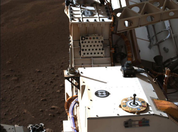 Mastcam-Z, a pair of zoomable cameras aboard NASA’s Perseverance rover, images its calibration target for the first time since the rover landed on Mars on February 18, 2021. The target is used as a reference marker so scientists can adjust the colors and settings on the cameras. Image credit: NASA / JPL-Caltech / MSSS / ASU.