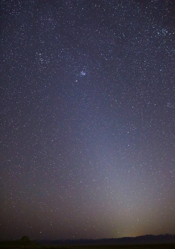 This photo shows the zodiacal light as it appeared on March 1, 2021, in Skull Valley, Utah, the United States; the Pleiades star cluster is visible near the top of the light column; Mars is just below that. Image credit: Bill Dunford / NASA.