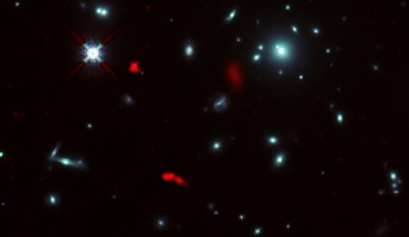This composite image, taken by the NASA/ESA Hubble Space Telescope and ALMA, shows the galaxy cluster RXCJ0600-2007 and lensed images of the galaxy RXCJ0600-z6 (red). Image credit: ALMA / ESO / NAOJ / NRAO / Fujimoto et al. / NASA / ESA / Hubble Team.