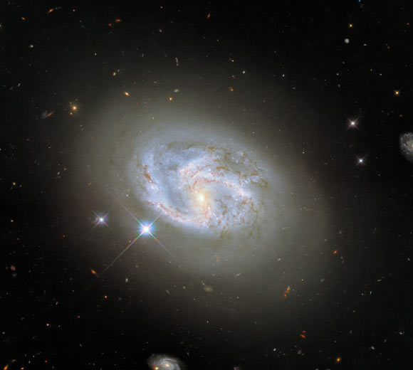 This Hubble image shows the spiral galaxy NGC 4680. The color image was made from separate exposures taken in the visible and infrared regions of the spectrum with Hubble’s Wide Field Camera 3 (WFC3). Four filters were used to sample various wavelengths. The color results from assigning different hues to each monochromatic image associated with an individual filter. Image credit: NASA / ESA / Hubble / Riess et al.