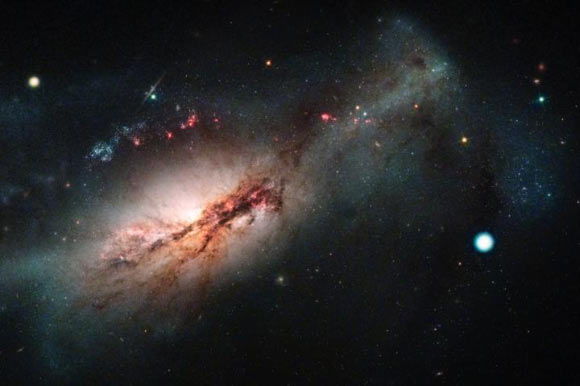 Las Cumbres/Hubble composite image of the electron-capture supernova SN 2018zd (the large white dot on the right) and the host starburst galaxy NGC 2146 (toward the left). Image credit: NASA / ESA / Hubble / STScI / J. DePasquale, Las Cumbres Observatory.