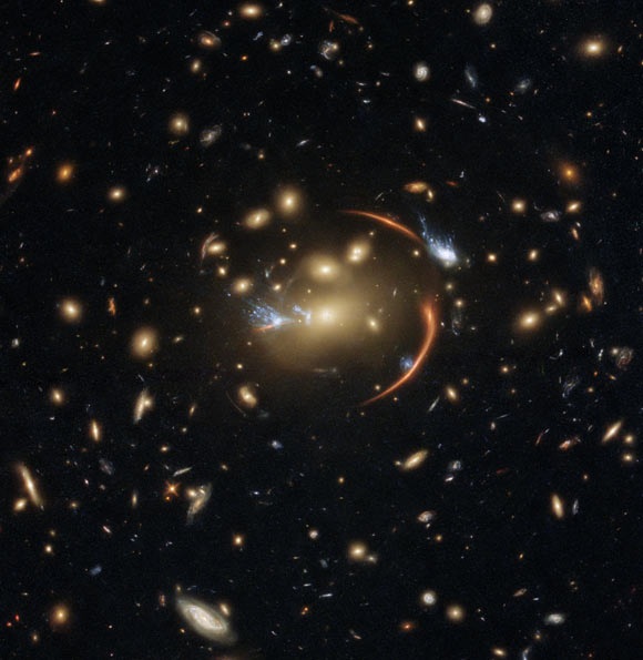 This Hubble image shows the galaxy cluster MACS J0138.0-2155, which is so massive that its gravity bent and magnified light streaming not only from an extremely distant background galaxy but also from a supernova event in this galaxy. The color image was made using observations from eight different filters spread across Hubble’s Advanced Camera for Surveys (ACS) and Wide Field Camera 3 (WFC3). The color results from assigning different hues to each monochromatic image associated with an individual filter. Image credit: NASA / ESA / Hubble / A. Newman / M. Akhshik / K. Whitaker.