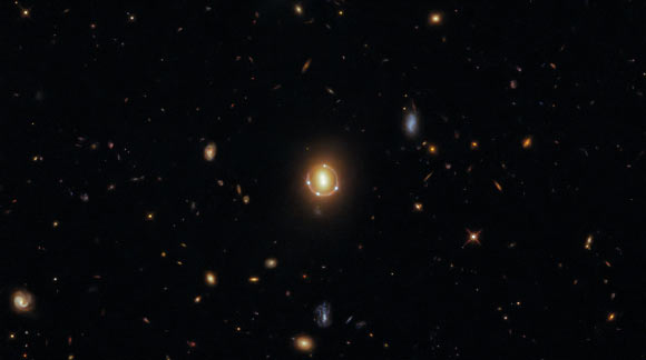 This Hubble image shows an Einstein ring formed by gravitationally lensed light from a distant quasar called 2M1310-1714. The color image is made up of observations from Hubble’s Wide Field Camera 3 (WFC3) in the infrared and optical parts of the spectrum. Three filters were used to sample various wavelengths. The color results from assigning different hues to each monochromatic image associated with an individual filter. Image credit: NASA / ESA / Hubble / T. Treu / Judy Schmidt, www.geckzilla.com.