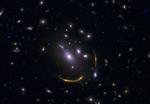 This composite image of the galaxy cluster MACSJ 0138 shows data from ALMA and Hubble. Image credit: ALMA / ESO / NAOJ / NRAO / S. Dagnello, NRAO / STScI / Whitaker et al.