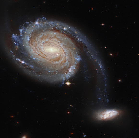 This composite image shows two interacting galaxies NGC 7752 and NGC 7753, collectively known as Arp 86. The image is composed of infrared, optical and ultraviolet observations from Hubble’s Advanced Camera for Surveys (ACS), the Dark Energy Camera (DECam) on the Victor M. Blanco 4-m Telescope, and the Sloan Digital Sky Survey (SDSS). Nine filters were used to sample various wavelengths. The color results from assigning different hues to each monochromatic image associated with an individual filter. Image credit: NASA / ESA / Hubble / Dark Energy Survey / J. Dalcanton.