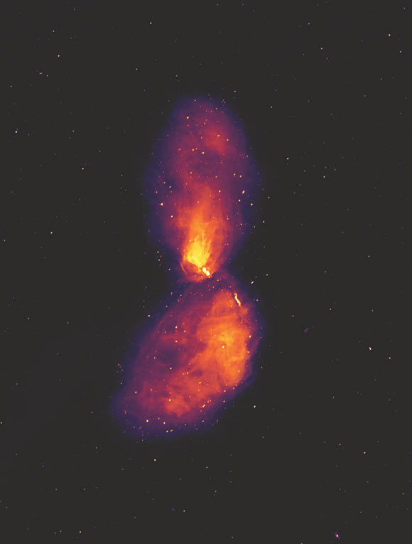 This MWA image shows Centaurus A at radio wavelengths, revealing vast lobes of plasma that reach far beyond the visible galaxy, which occupies only a small patch at the center of the image. The dots in the background are not stars, but radio galaxies much like Centaurus A, at far greater distances. Image credit: Ben McKinley, ICRAR & Curtin University / Connor Matherne, Louisiana State University.