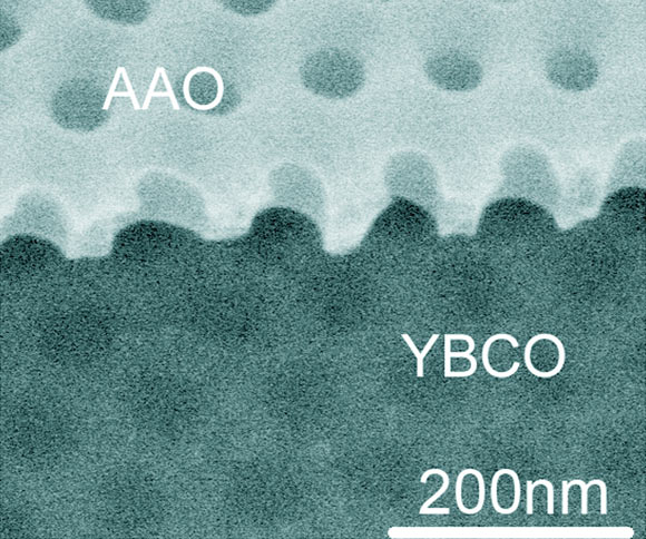 Scanning electron microscopy image of a nanopatterned YBa2Cu3O7−δ (YBCO) thin film. The 12-nm-thick nanopatterned YBCO thin film was fabricated by reactive ion etching through an anodic aluminium oxide (AAO) membrane directly placed atop the YBCO. By RIE, the anodized aluminium oxide pattern of a triangular array of holes with ~70-nm diameter and ~103-nm period was duplicated onto the YBCO film. Image credit: Yang et al., doi: 10.1038/s41586-021-04239-y.