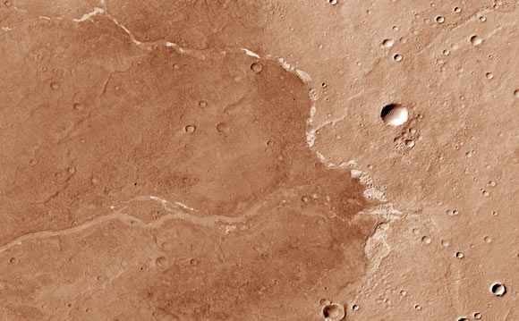 This image from the Context Camera onboard NASA’s Mars Reconnaissance Orbiter shows Bosporos Planum on Mars; the white specks are salt deposits found within a dry channel; the largest impact crater in the scene is nearly 1.5 km (one mile) across. Image credit: NASA / JPL-Caltech / MSSS.