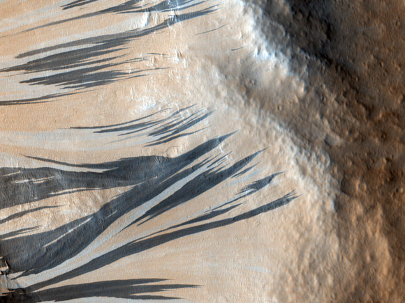 These dark slope streaks resulted from dust avalanches in Acheron Fossae, Mars. The HiRISE camera aboard NASA’s Mars Reconnaissance Orbiter captured them on December 3, 2006. Image credit: NASA / JPL-Caltech / University of Arizona.