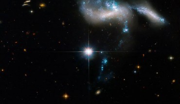 This Hubble image shows Hickson Compact Group 31, a group of four galaxies located some 166 million light-years away in the constellation of Eridanus. The bright, distorted object is actually two colliding dwarf galaxies. The bluish star clusters have formed in the streamers of debris pulled from the galaxies and at the site of their head-on collision. The cigar-shaped object to the right is another member of the group. A bridge of star clusters connects the trio. A longer rope of bright star clusters points to the fourth member of the group. The bright object in the center is a foreground star. Image credit: NASA / ESA / J. Charlton, Pennsylvania State University / G. Kober, NASA’s Goddard Space Flight Center / Catholic University of America.