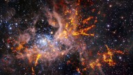 This composite image shows the Tarantula Nebula. The background image, taken in the infrared, is itself a composite: it was captured by the HAWK-I instrument on ESO’s Very Large Telescope (VLT) and the Visible and Infrared Survey Telescope for Astronomy (VISTA), shows bright stars and light, pinkish clouds of hot gas. The bright red-yellow streaks that have been superimposed on the image come from radio observations taken by the ALMA, revealing regions of cold, dense gas which have the potential to collapse and form stars. The unique web-like structure of the gas clouds led astronomers to the nebula’s spidery nickname. Image credit: ESO / ALMA / NAOJ / NRAO / Wong et al. / M.-R. Cioni / VISTA Magellanic Cloud Survey / Cambridge Astronomical Survey Unit.