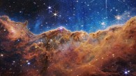 This landscape of ‘mountains’ and ‘valleys’ speckled with glittering stars is actually the edge of the Carina Nebula, a huge star-forming region some 7,500 light-years away in the constellation of Carina. Captured in infrared light by Webb, this image reveals for the first time previously invisible areas of star birth. Called the Cosmic Cliffs, Webb’s seemingly 3D picture looks like craggy mountains on a moonlit evening. In reality, it is the edge of the giant, gaseous cavity within the Carina Nebula, and the tallest ‘peaks’ in this image are about 7 light-years high. The cavernous area has been carved from the nebula by the intense ultraviolet radiation and stellar winds from extremely massive, hot, young stars located in the center of the bubble, above the area shown in this image. Image credit: NASA / ESA / CSA / STScI.