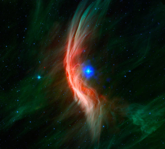 Zeta Ophiuchi was once in close orbit with another star, before being ejected when this companion was destroyed in a supernova explosion; infrared data from Spitzer reveal a spectacular shock wave (red and green) that was formed by matter blowing away from the star’s surface and slamming into gas in its path; data from Chandra (blue) show a bubble of X-ray emission located around the star, produced by gas that has been heated by the shock wave to tens of millions of degrees. Image credit: NASA / CXC / University of Cambridge / Sisk-Reynés et al. / NSF / NRAO / VLA / PanSTARRS.