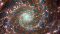 Messier 74, a grand design spiral galaxy located 32 million light-years away in the constellation of Pisces, shines at its brightest in this combined optical/mid-infrared image, featuring Webb and Hubble data. The red colors mark dust threaded through the arms of the galaxy, lighter oranges being areas of hotter dust. The young stars throughout the arms and the nuclear core are picked out in blue. Heavier, older stars towards the galaxy’s center are shown in cyan and green, projecting a spooky glow from the core of Messier 74. Bubbles of star formation are also visible in pink across the arms. Image credit: NASA / ESA / CSA / Webb / Hubble / J. Lee / PHANGS-JWST Team / R. Chandar / J. Schmidt.