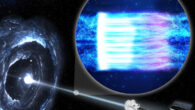 This illustration shows the IXPE spacecraft (right) observing the blazar Markarian 501 (left). A blazar is a black hole surrounded by a disk of gas and dust with a bright jet of high-energy particles pointed toward Earth. The inset illustration shows high-energy particles in the jet (blue). When the particles hit the shock wave, depicted as a white bar, the particles become energized and emit X-rays as they accelerate. Moving away from the shock, they emit lower-energy light: first visible, then infrared, and radio waves. Farther from the shock, the magnetic field lines are more chaotic, causing more turbulence in the particle stream. Image credit: NASA / Pablo Garcia.