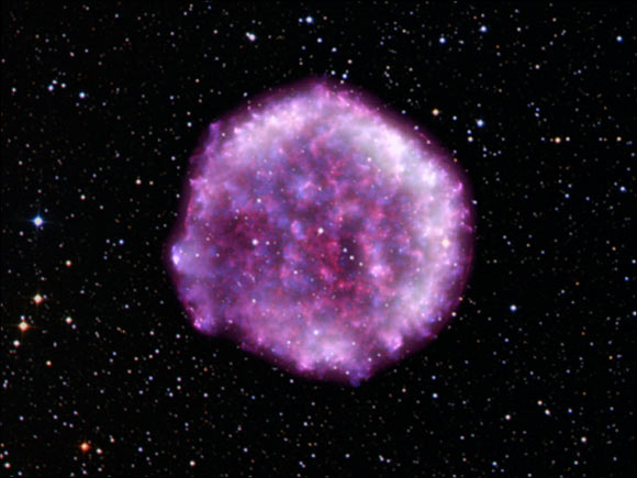 This image shows Tycho’s SNR, which is located between 8,000 and 10,000 light-years away in the constellation of Cassiopeia. IXPE data (dark purple and white) have been combined with data from NASA’s Chandra X-ray Observatory (red and blue) and overlaid with the stars in the field of view as captured by the Digitized Sky Survey. Image credit: IXPE / NASA / ASI / MSFC / INAF / Ferrazzoli et al. / Chandra / CXC / RIKEN / GSFC / Sato et al. / DSS / SAO / K. Arcand, L. Frattare & N. Wolk.