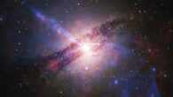 This composite image shows the elliptical galaxy Centaurus A: blue color shows X-ray light captured by Chandra, orange represents X-rays detected by IXPE, and optical light seen by ESO is colored white and gray. Image credit: NASA / MSFC / IXPE / Ehlert et al. / CXC / SAO / ESO / WFI / J.Schmidt.