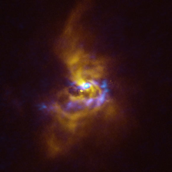 This composite image shows V960 Mon, a young star located over 5,000 light-years away in the constellation of Monoceros. Observations obtained using the Spectro-Polarimetric High-contrast Exoplanet REsearch (SPHERE) instrument on ESO’s VLT, represented in yellow in this image, show that the dusty material orbiting V960 Mon is assembling together in a series of intricate spiral arms extending to distances greater than the entire Solar System. Meanwhile, the blue regions represent data obtained with ALMA. The ALMA data peers deeper into the structure of the spiral arms, revealing large dusty clumps that could contract and collapse to form giant planets roughly the size of Jupiter via a process known as gravitational instability. Image credit: ESO / ALMA / NAOJ / NRAO / Weber et al.