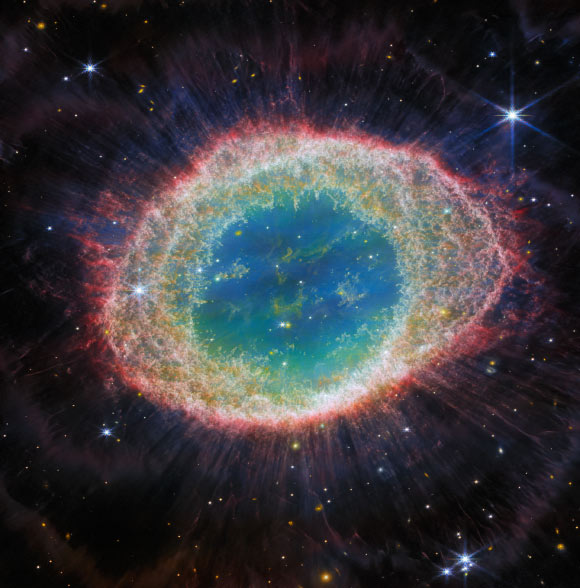 This image from Webb’s NIRCam instrument shows the Ring Nebula. The nebula’s inner cavity hosts shades of blue and green, while the detailed ring transitions through shades of orange in the inner regions and pink in the outer region. The ring’s inner region has distinct filament elements. Image credit: NASA / ESA / CSA / Webb / M. Barlow / N. Cox / R. Wesson.