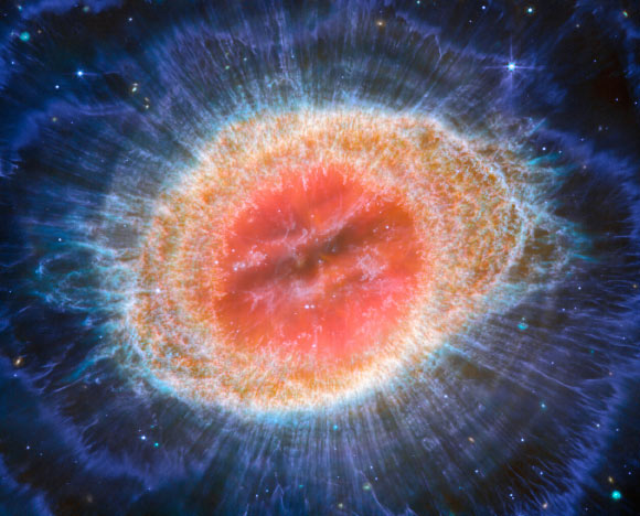 This image from Webb’s MIRI instrument shows the Ring Nebula. The nebula’s inner cavity hosts shades of red and orange, while the detailed ring transitions through shades of yellow in the inner regions and blue/purple in the outer region. Image credit: NASA / ESA / CSA / Webb / M. Barlow / N. Cox / R. Wesson.