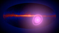 This artist’s concept shows the entire sky in gamma rays with magenta circles illustrating the uncertainty in the direction from which more high-energy gamma rays than average seem to be arriving. In this view, the plane of our Milky Way Galaxy runs across the middle of the map. The circles enclose regions with a 68% (inner) and a 95% chance of containing the origin of these gamma rays. Image credit: NASA’s Goddard Space Flight Center.