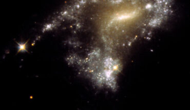 The galaxy AM 1054-325 has been distorted into an S-shape from a normal pancake-like spiral shape by the gravitational pull of a neighboring galaxy, seen in this Hubble image; a consequence of this is that clusters of newborn stars form along a stretched-out tidal tail for thousands of light-years, resembling a string of pearls. Image credit: NASA / ESA / STScI / Jayanne English, University of Manitoba.