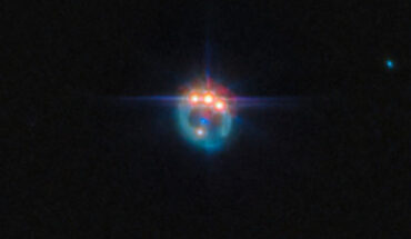 This Webb image shows the RX J1131-1231 galaxy distorted by gravitational lensing into a dim ring; at the top of the ring are three very bright spots with diffraction spikes coming off them, right next to each other; these are copies of a single quasar in the lensed galaxy, duplicated by the gravitational lens; in the center of the ring, the elliptical galaxy doing the lensing appears as a small blue dot. Image credit: NASA / ESA / CSA / Webb / A. Nierenberg.