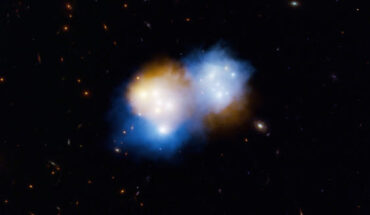 This artist’s concept shows what happened when two massive clusters of galaxies, collectively known as MACS J0018.5+1626, collided: the dark matter in the galaxy clusters (blue) sailed ahead of the associated clouds of hot gas, or normal matter (orange); both dark matter and normal matter feel the pull of gravity, but only the normal matter experiences additional effects like shocks and turbulence, which slow it down during collisions. Image credit: W.M. Keck Observatory / Adam Makarenko.