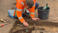 Dr. Elias Witte Thomasen uncovering the massive weapon offering at the site of Løsning Søndermark, Hedensted, Denmark. Image credit: Vejle Museums.