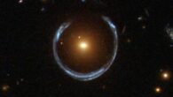 This Hubble image shows the Cosmic Horseshoe gravitational lens (to the right from the center): the newly-discovered ultramassive blackhole lies at the center of the orange galaxy; far behind it is a blue galaxy that is being warped into the horseshoe shaped ring by distortions in spacetime created by the immense mass of the foreground orange galaxy. Image credit: NASA / ESA / Hubble.