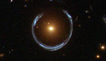 This Hubble image shows the Cosmic Horseshoe gravitational lens (to the right from the center): the newly-discovered ultramassive blackhole lies at the center of the orange galaxy; far behind it is a blue galaxy that is being warped into the horseshoe shaped ring by distortions in spacetime created by the immense mass of the foreground orange galaxy. Image credit: NASA / ESA / Hubble.