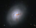 This Hubble image reveals the lenticular galaxy NGC 1266; reddish-brown clumps and filaments of dust partially obscure the galaxy’s full face, while red, blue, and orange light from distant galaxies shines through its diffuse outer regions and dots the inky-black background. Image credit: NASA / ESA / K. Alatalo, STScI / G. Kober, NASA & Catholic University of America.