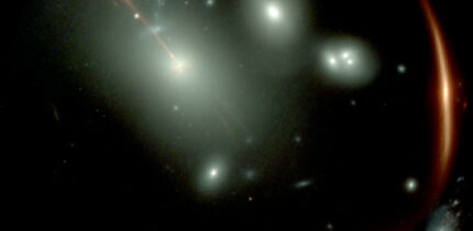 This Webb image shows the highly distorted red galaxy MRG-M0138 seen through a foreground cluster of galaxies (white sources). Image credit: NASA / ESA / CSA / Webb.
