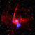 This composite image contains X-rays from Chandra and XMM-Newton missions (shown in blue) as well as radio data from the MeerKAT telescope (shown in red) in South Africa. These have been combined with an optical image from the Pan-STARRS telescopes in Hawai’i (red, green, and blue). Image credit: NASA / CXC / UCLA / Zhu et al. / ESA / XMM-Newton / PanSTARRS / MeerKAT / CSA / STScI / SAO / L. Frattare & P. Edmonds.