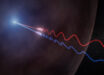 This illustration depicts Faraday rotation in the afterglow of a gamma-ray burst. A powerful jet (upper left) sends polarized radio waves outward through the thin wall of a surrounding bubble of magnetized gas called an HII region. As the light passes through this material, its polarization angle is twisted by the magnetic field. Because the effect is stronger at longer wavelengths, the red and blue waves, which represent different radio wavelengths, exit the bubble oscillating in different directions. By measuring this difference, astronomers were able to map the magnetic environment surrounding GRB 260310A for the first time. Image credit: NSF / AUI / NRAO / M. Weiss